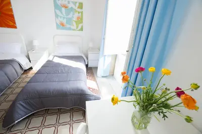 a room with two beds and a vase with flowers at Aria Rooms in Palermo