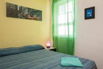 a bedroom with a bed and a window with a green curtain at Casa Ibiscus x2 in Palermo
