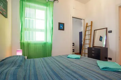 a bedroom with a bed with a green curtain and a window at Casa Ibiscus x2 in Palermo