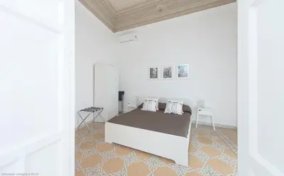 a white bedroom with a bed and a table at Dimora CentroWell in Palermo