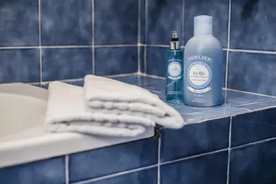 a bottle of soap and towels on a shelf in a bathroom at LuminHouse Mondello Arancia in Mondello