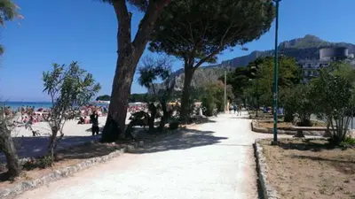 a beach with a bunch of people sitting on the beach at Near the beach in Palermo