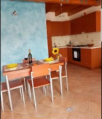 a kitchen with a wooden table and chairs and a table and a kitchen with at Casa Vacanza Brigida in Scopello