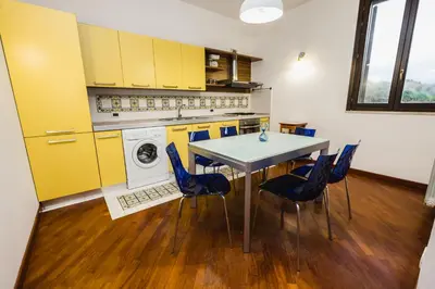 a kitchen with yellow cabinets and a table and chairs at LuminHouse Villa Mondello in Mondello