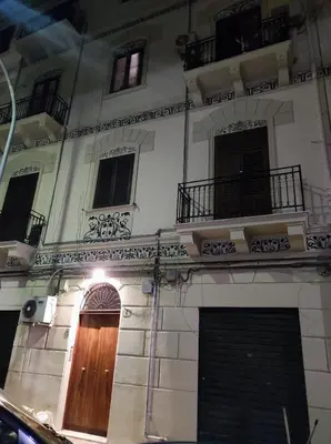 a large white building with a wooden door and windows at Pretty house in Palermo