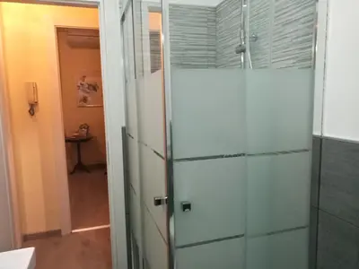 a glass shower door in a bathroom with a hallway at Pretty house in Palermo