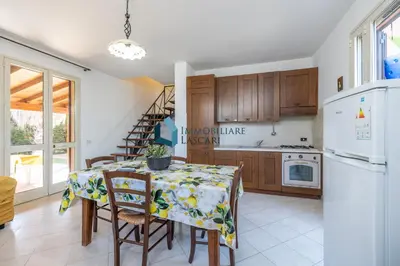 a kitchen with a table and chairs and a refrigerator at Villa Siragusa con piscina condominiale in Campofelice di Roccella