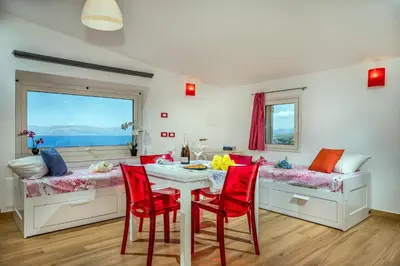 a dining room with red chairs and a table at La Finestra sul Mare dello Zingaro in Scopello