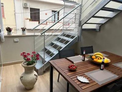 a room with a table with a bowl of fruit and a staircase at Caporama in Terrasini