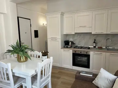 a kitchen with white cabinets and a table with a plant at Caporama in Terrasini