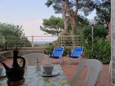 a table and chairs on a patio with a view of the ocean at Casa in villa vista mare in Palermo
