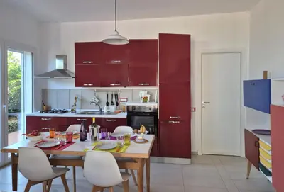 a kitchen with red cabinets and a table and chairs at Casa in villa vista mare in Palermo