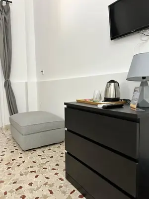a bedroom with a dresser with a chair and a tv at Casa Genna in Isola delle Femmine