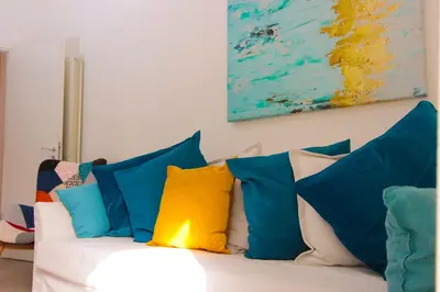 a white couch with blue and yellow pillows on it at Le Casette di Marcì in Palermo
