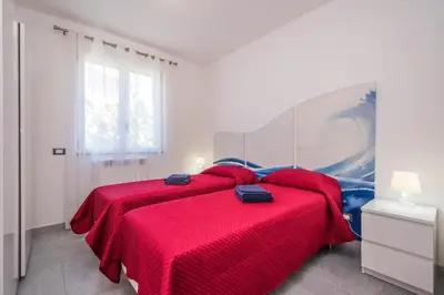 a bedroom with a large red bed with red sheets at Villa Sara in Lascari