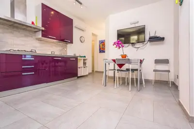 a kitchen with a table and a tv on the wall at Villa Sara in Lascari