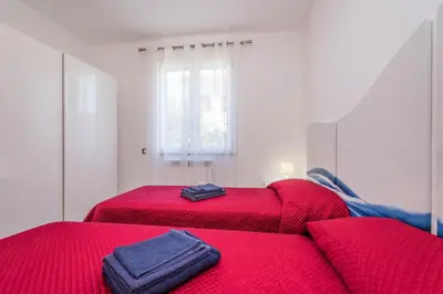 two beds with red sheets in a room with a window at Villa Sara in Lascari