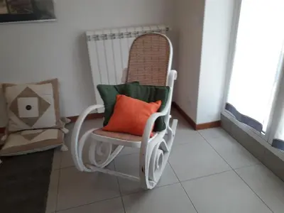 a white rocking chair with an orange pillow on it at Principessa Jolanda in Mondello