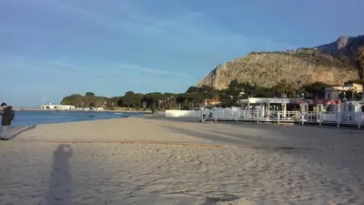 a person standing on a beach with a mountain in the background at Principessa Jolanda in Mondello