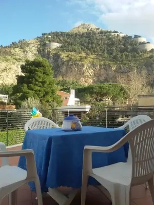 a blue table with chairs and a mountain in the background at Principessa Jolanda in Mondello