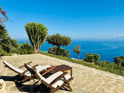 two chairs and a table on a patio with the ocean at Baglio La Luna - B&B in San Vito lo Capo