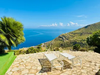 a bench sitting on top of a hill with the ocean at Baglio La Luna - B&B in San Vito lo Capo
