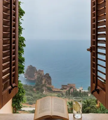 an open book on a table with a view of the ocean at Torre Bennistra in Scopello