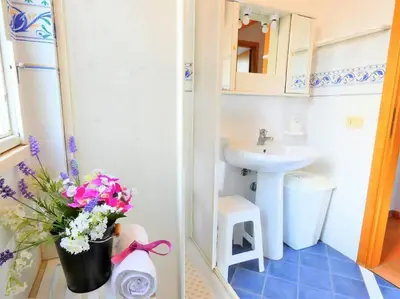 a bathroom with a sink and a vase of flowers at Villa Indipendente Jacuzzi Giardino Clima WiFi in Castellammare del Golfo