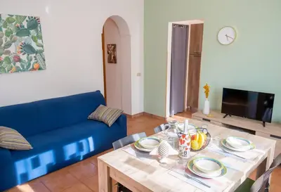 a living room with a table and a blue couch at Villa Indipendente Jacuzzi Giardino Clima WiFi in Castellammare del Golfo