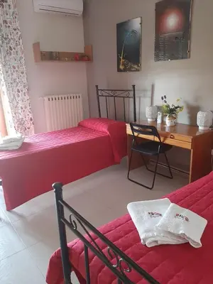 a bedroom with two beds and a table and a desk at La casa di Bia in Corleone