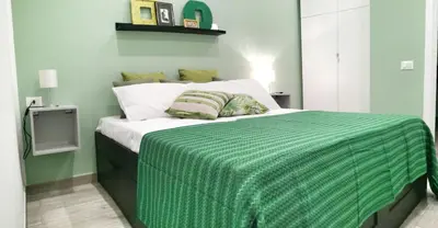 a bedroom with a bed with a green blanket on it at A Palermo Sono in Palermo