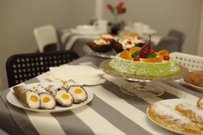 a table topped with cakes and desserts on plates at Mantegna Rooms in Palermo