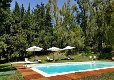 a swimming pool with two umbrellas and chairs at Masseria Rossella in Piana degli Albanesi