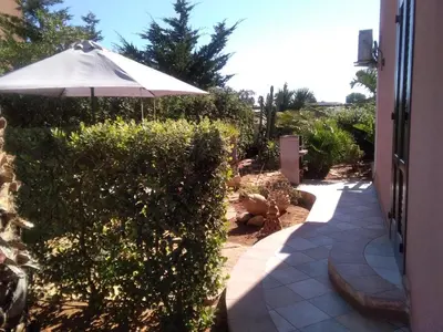 a patio with an umbrella next to a hedge at VILLA TREROSE by Trerose Properties - Villa centrale con wi-fi e posto auto privato gratuiti in San Vito lo Capo