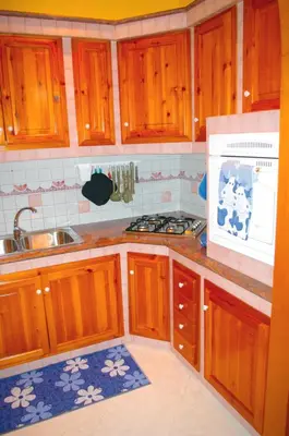 a kitchen with wooden cabinets and a sink and a stove at La Casetta di Andrea & Vale in Termini Imerese