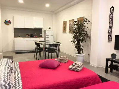 a room with a red bed and a kitchen with a table at Casa4Casa in Palermo