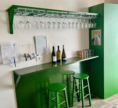 a green bar with two green stools and wine glasses at Locanda Sette Fate SPA e Solarium in Palermo