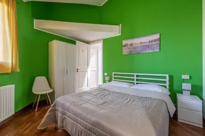 a green bedroom with a bed and a chair at Bouganville Home Mondello in Mondello