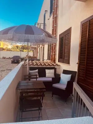 a patio with tables and chairs and an umbrella at Sicilia Vacation in San Vito lo Capo