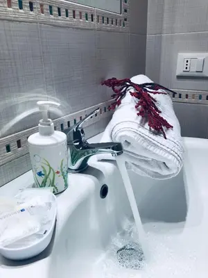a bathroom sink with water running from a faucet at Sicilia Vacation in San Vito lo Capo