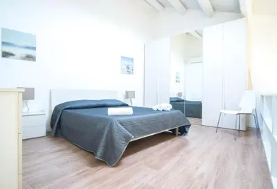 a white bedroom with a bed and a wooden floor at Casa Gelsomino in Palermo