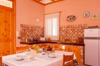 a kitchen with a white table and a white refrigerator at Villa Cycas Costamante in Castellammare del Golfo