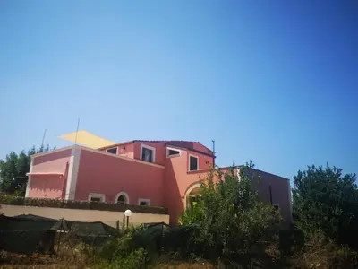 a pink building with a blue sky in the background at Villa Plaia in Castellammare del Golfo