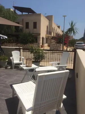 a group of white chairs and tables on a patio at Casa Rosita in San Vito lo Capo