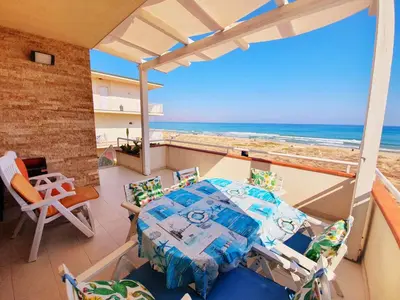 a balcony with a table and chairs and the ocean at Castellammare Holiday in Alcamo Marina
