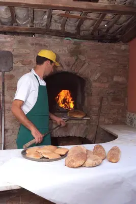 a man is making bread in a brick oven at Agriturismo Al Poggetto in Piana degli Albanesi