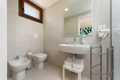 a white bathroom with a sink and a toilet at Residence Le Piscine in San Vito lo Capo