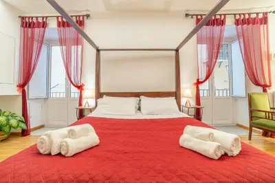 a bedroom with a red bed with two white towels at Natoli Apartments in Palermo