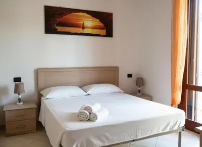 two beds in a room with a door at Casa Vacanze Monacò in San Vito lo Capo