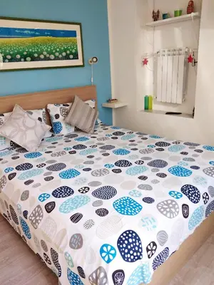 a bedroom with a bed with a blue and white comforter at Il Giardino di Laura Private Rooms Mondello in Mondello